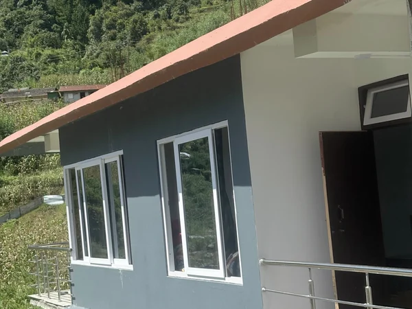 Grey-walled newer building of the homestay with a small balcony