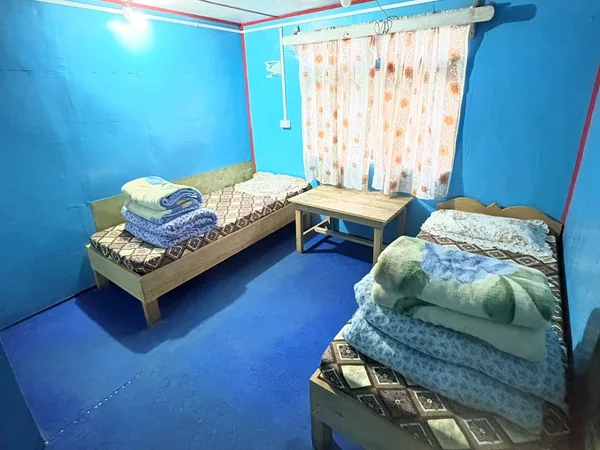 Bright blue wooden room with twin beds and a small table
