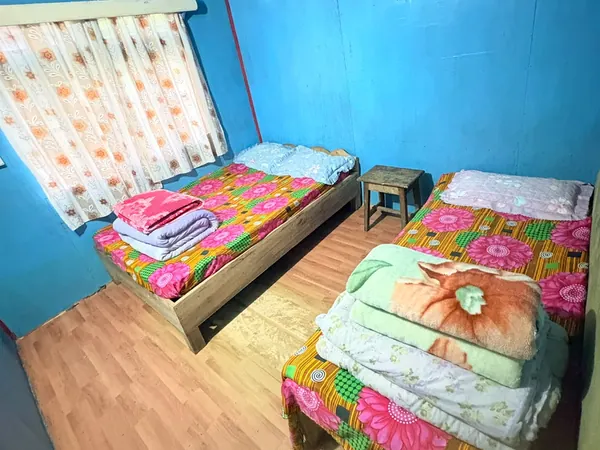 Wooden-floored room with two beds and folded blankets